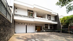 A modern two-story house with a spacious driveway, a balcony on the upper floor, and a large garage door. - KoolKost near Padjadjaran University (Bandung)