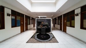 A corridor with a skylight, a central fountain, and wooden doors on both sides. - KoolKost near Padjadjaran University (Bandung)