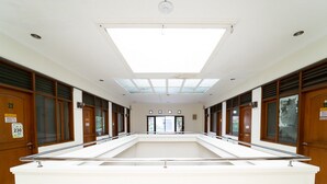 A spacious hotel lobby with a central reception desk, wooden paneling, and large windows allowing natural light. - KoolKost near Padjadjaran University (Bandung)