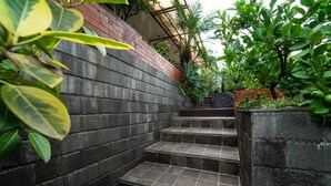 A set of stone steps leading up a brick wall, surrounded by lush greenery and plants. - KoolKost near BTC Fashion Mall 2 (Bandung)