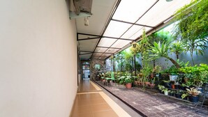 A corridor with a tiled floor, a glass ceiling, and potted plants along the walls. - KoolKost near BTC Fashion Mall 2 (Bandung)