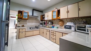 A kitchen with light-colored cabinets, a microwave, a toaster, and a stove. - KoolKost near BTC Fashion Mall 2 (Bandung)