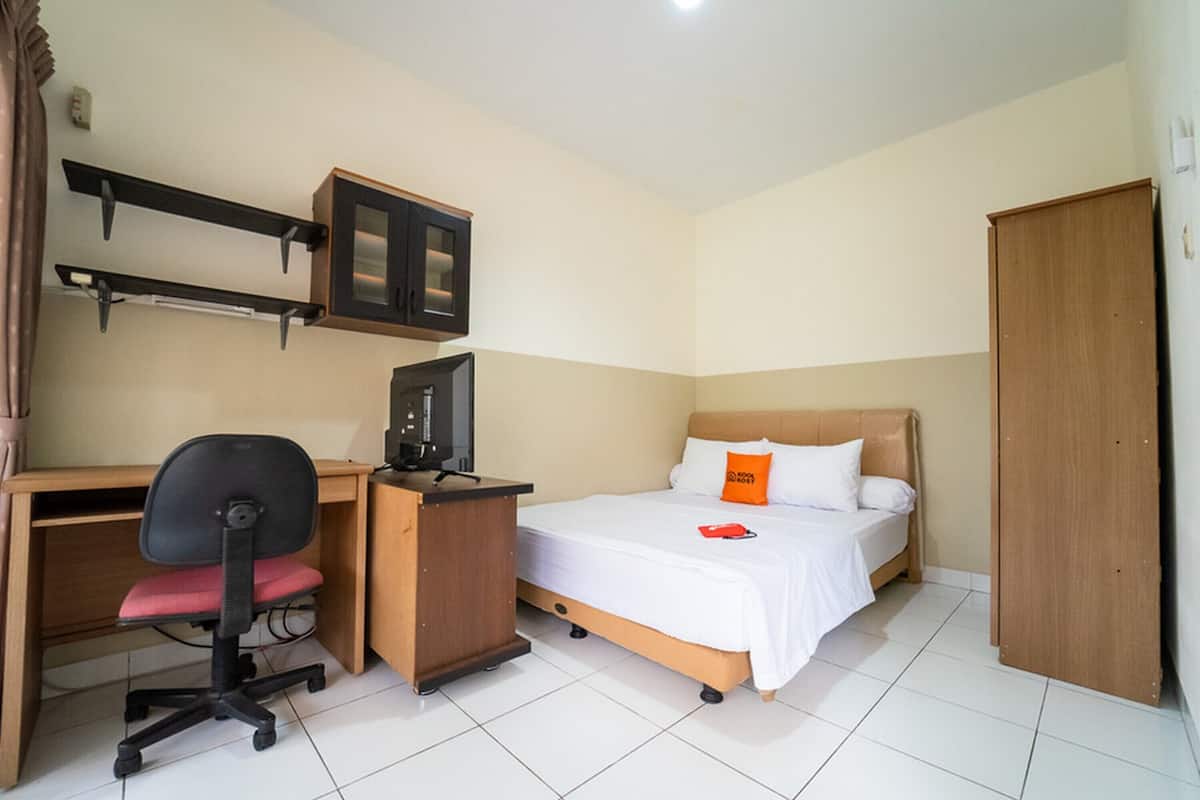 Un dormitorio con cama, escritorio, silla, armario y televisor.