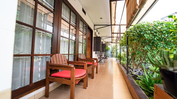 A corridor with wooden chairs and tables, large windows, and a garden area with plants. - KoolKost near BTC Fashion Mall 2 (Bandung)