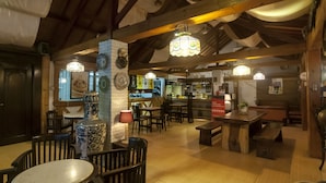 L’intérieur d’un restaurant est agrémenté de poutres en bois, de luminaires suspendus et propose différents types de sièges, notamment des tables et des bancs.