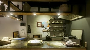 Une cuisine dotée d’un plan de travail en marbre, de divers appareils électroménagers et d’étagères remplies d’assiettes et d’ustensiles de cuisine.
