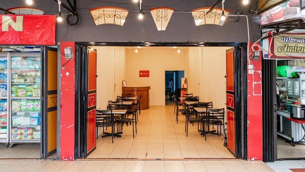 A restaurant with a red and black exterior, multiple tables and chairs, and a visible entrance. - RedDoorz Syariah @ Jalan Setiabudi Medan 3 (Medan)