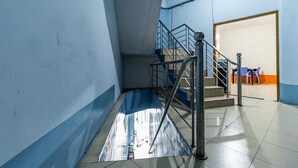 A stairwell with metal railings, a blue mat at the bottom, and a door leading to a room with a table and chairs. - RedDoorz Syariah @ Jalan Setiabudi Medan 3 (Medan)
