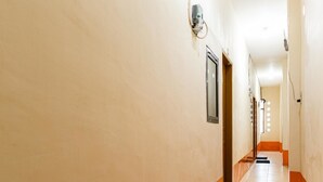 A long, narrow hotel hallway with a tiled floor and a light-colored wall. - RedDoorz Syariah @ Jalan Setiabudi Medan 3 (Medan)