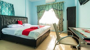 A bedroom with a bed, a desk, a chair, and an air conditioning unit. - RedDoorz Syariah @ Jalan Setiabudi Medan 3 (Medan)