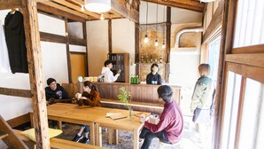 Een rustiek interieur met houten balken, een houten tafel en banken. Er is een bar met flessen en een wereldbol.
