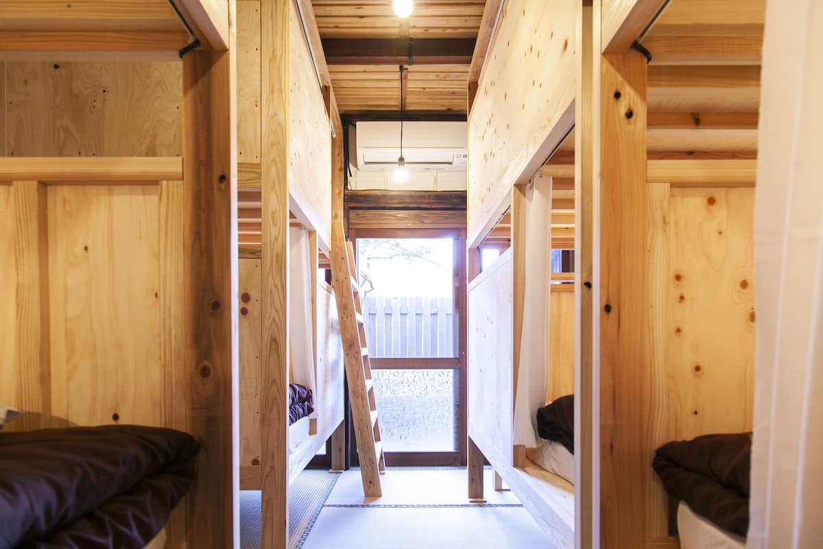 Un intérieur en bois avec des lits superposés et une porte centrale donnant sur un espace extérieur.