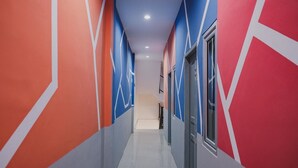 A hallway with geometric wall patterns and a staircase leading to an upper level. - RedDoorz @ Jalan Sukabangun 2 Palembang (Palembang)