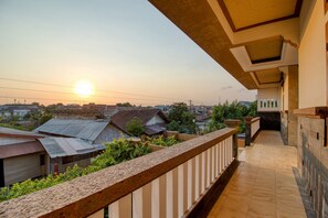 A balcony with a view of houses and the sun setting in the background. - RedDoorz Plus near Lempuyangan Station 4 (Yogyakarta)