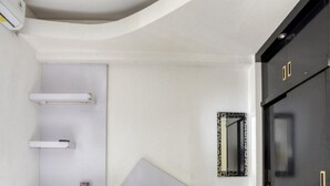 Una habitación de hotel con cama, escritorio, silla, armario y espejo.