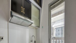 Cocina compacta con encimera negra, pileta de acero inoxidable y alacenas blancas.