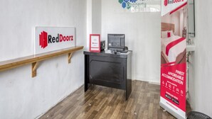 Zona de recepción de un hotel con un mostrador, una computadora y un letrero de RedDoorz.
