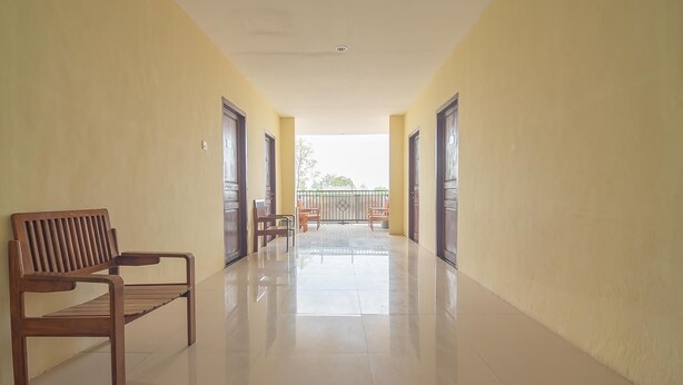 A corridor with a bench, chairs, and a view to the outside. - RedDoorz @ Jalan Cilik Riwut Kapuas (Kualakapuas)