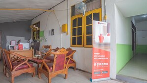 A room with a dining table and chairs, a standing fan, and a RedDoorz advertisement. - RedDoorz @ Jalan Cilik Riwut Kapuas (Kualakapuas)