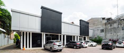 A parking area with several cars parked in front of a building with large windows and a flat roof.