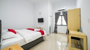 Un dormitorio con cama, escritorio, silla, televisión y aire acondicionado.