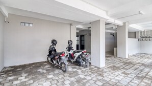 A clean, modern indoor space with a tiled floor and white walls, featuring two motorcycles parked against the wall. - RedDoorz Syariah near Galeria Mall Yogyakarta (Yogyakarta)