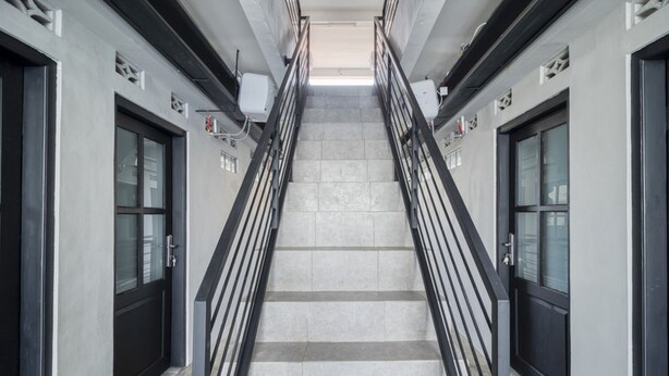 A modern staircase with metal railings, leading to a landing with doors on either side. - RedDoorz Syariah near Galeria Mall Yogyakarta (Yogyakarta)