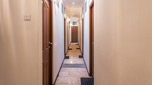 A narrow hallway with wooden doors on both sides, a tiled floor, and a light fixture above the doorways. - RedDoorz near Alun Alun Bandung 2 (Bandung)