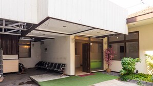 A building with a covered entrance, a waiting area with chairs, and a small garden with a potted plant. - RedDoorz near Alun Alun Bandung 2 (Bandung)