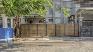 A paved courtyard with a tree, a blue structure, and a gated fence. - RedDoorz near Widya Mandala University (Surabaya)