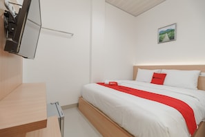 A modern hotel room with a wooden bed frame, white bedding, and a red accent.