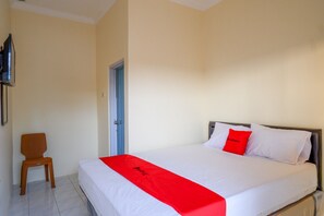 Une chambre d’hôtel avec un lit, une chaise et un téléviseur fixé au mur.