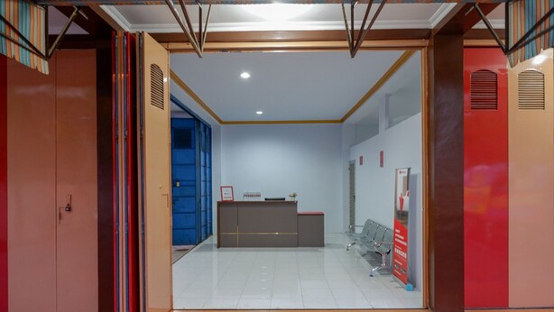 A reception area with a desk, chairs, and a blue door. - RedDoorz near GOR Satria 3 (Purwokerto)