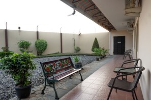 Une terrasse extérieure avec un banc, des chaises et des plantes en pot.