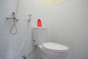 Une salle de bain avec des toilettes, une douche et un sac rouge accroché au mur.