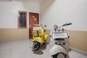 Una habitación con dos scooters antiguos, una puerta de madera y un cuadro en la pared.