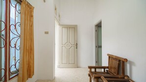 A hallway with a wooden bench, a door, and a window with curtains. - RedDoorz near Watervang Lubuk Linggau 2 (Lubuklinggau)