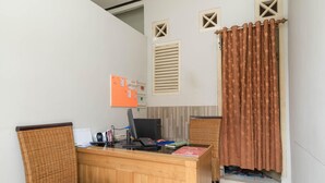 A reception area with a wooden desk, two wicker chairs, a computer, and a bulletin board. - RedDoorz near Watervang Lubuk Linggau 2 (Lubuklinggau)