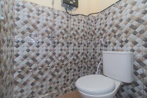 A bathroom with a patterned tile wall, a toilet, and a shower with a hose.