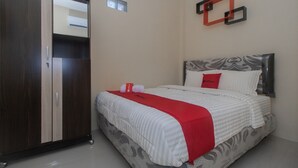 Une chambre à coucher comprenant un lit, une armoire et une étagère fixée au mur.