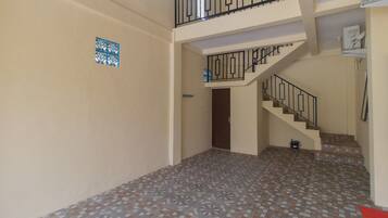 A spacious hallway with patterned floor tiles, a staircase with black railings, and a door leading to another room.
