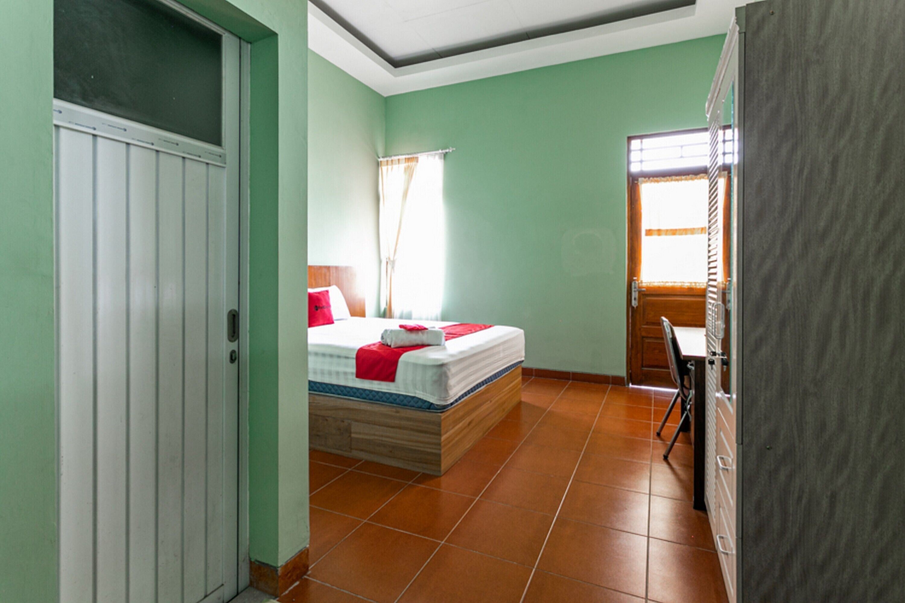 Una habitación con una cama, una silla, una mesa y una puerta.