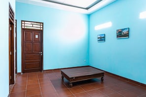 Ein Zimmer mit Holztür, einem Bett und zwei gerahmten Bildern an der Wand.