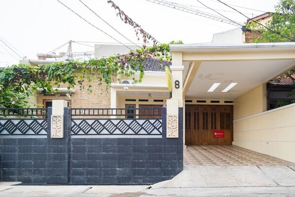 A residential building with a gated entrance, a number '8' on the wall, and a covered driveway. - RedDoorz Syariah near Grand Kota Bintang (Bekasi)