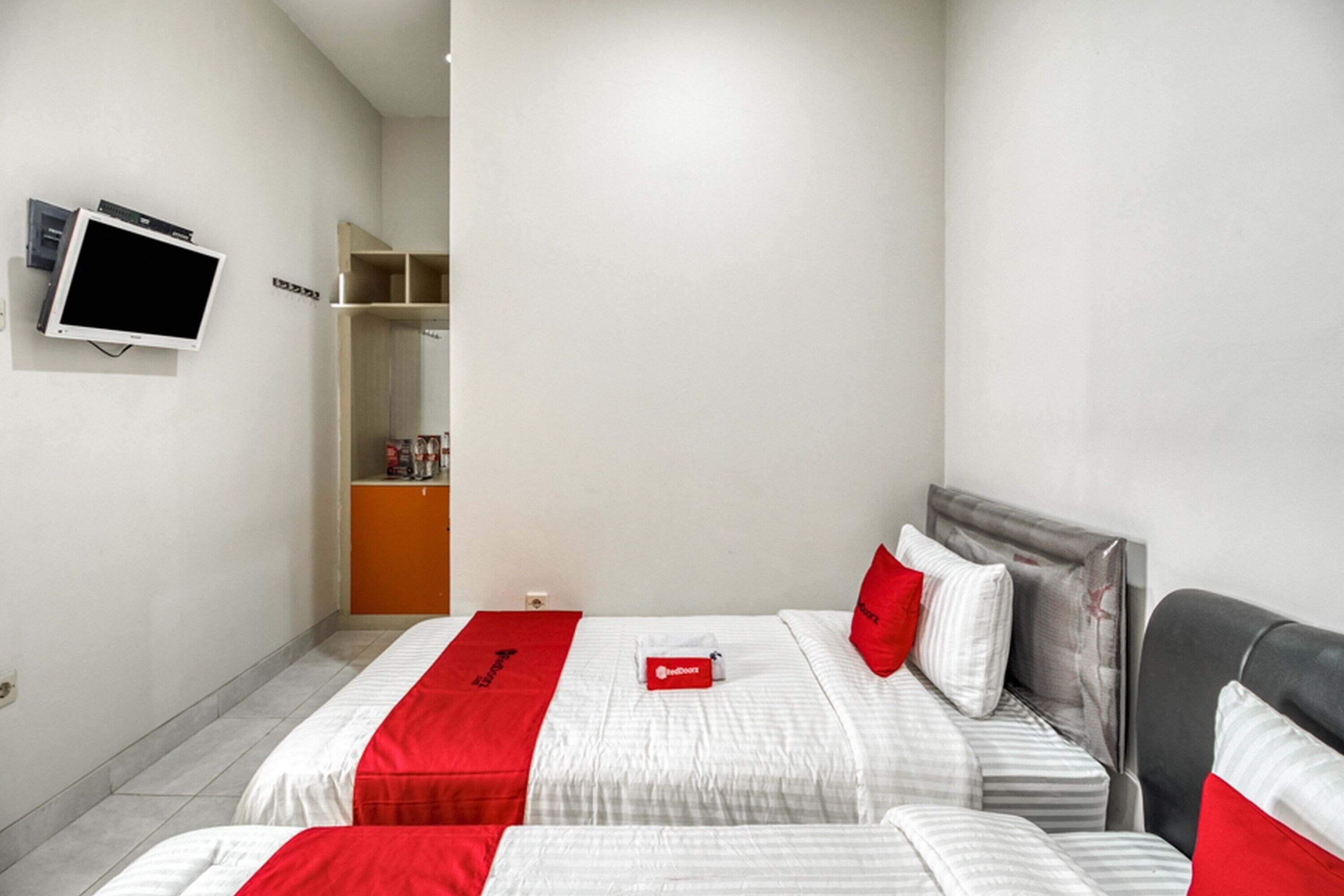 Une chambre d’hôtel avec deux lits, une télévision et une armoire.