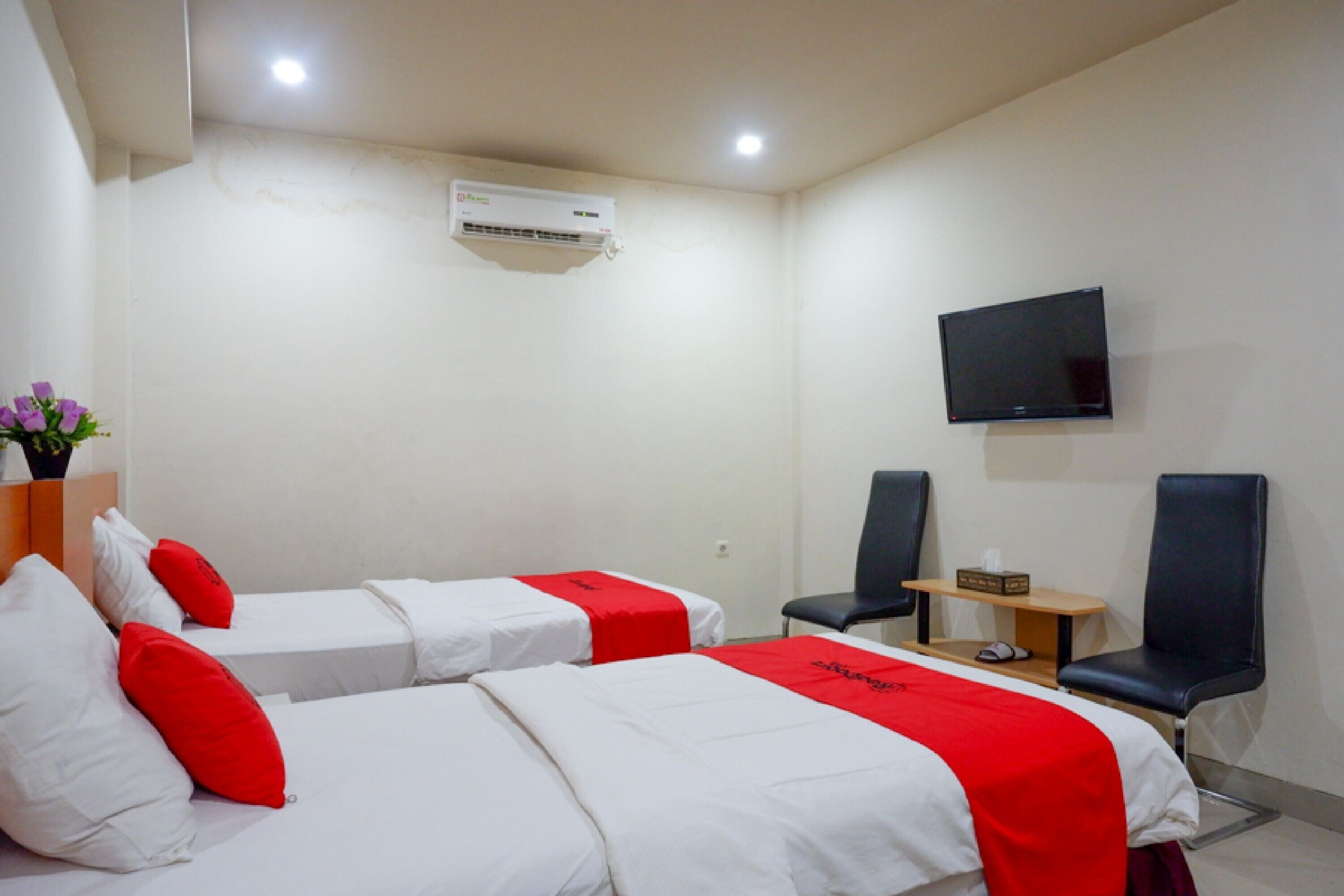 A hotel room with two beds, a TV, and a desk with a chair.