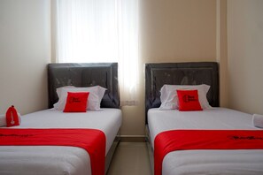 Dos camas individuales con ropa de cama y almohadas rojas, una colcha roja y una almohada Red Doorze en cada cama.