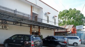 A building with a covered walkway and parked cars in front. - RedDoorz near Pasar Baru Mamuju (Mamuju)