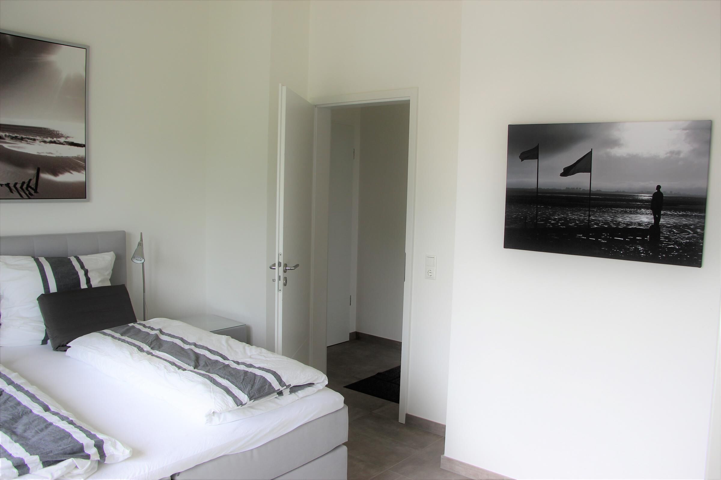 A bedroom with a bed, a nightstand, and a painting of a beach scene.