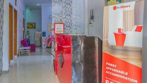 A hotel reception area with a modern design, including a reception desk, a chandelier, and a framed picture on the wall. - RedDoorz Syariah @ Puri Kalijaga Street (Cirebon)